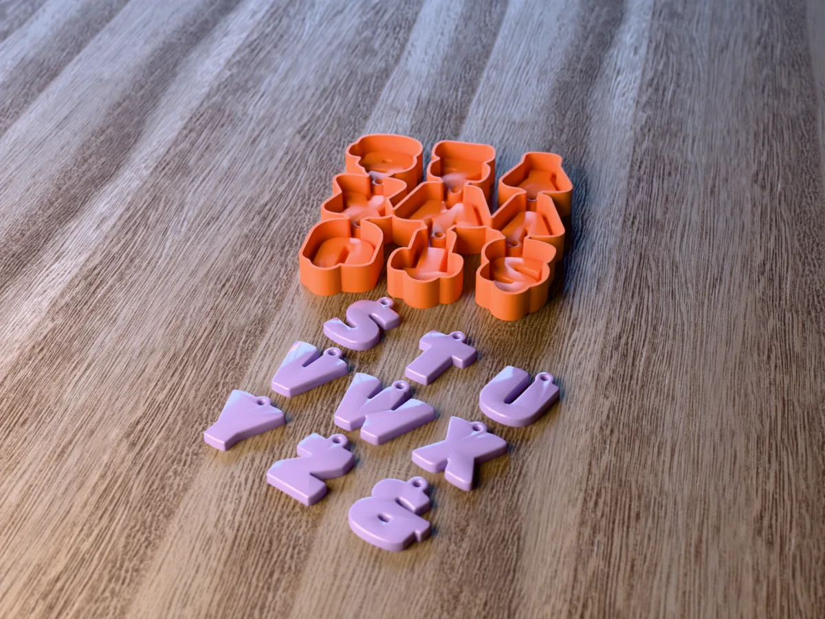 3D render of the printed caster for an alphabet resin keychain mold with the letters S to Z and an ampersand, and nine lilac bubble letter keychains in front