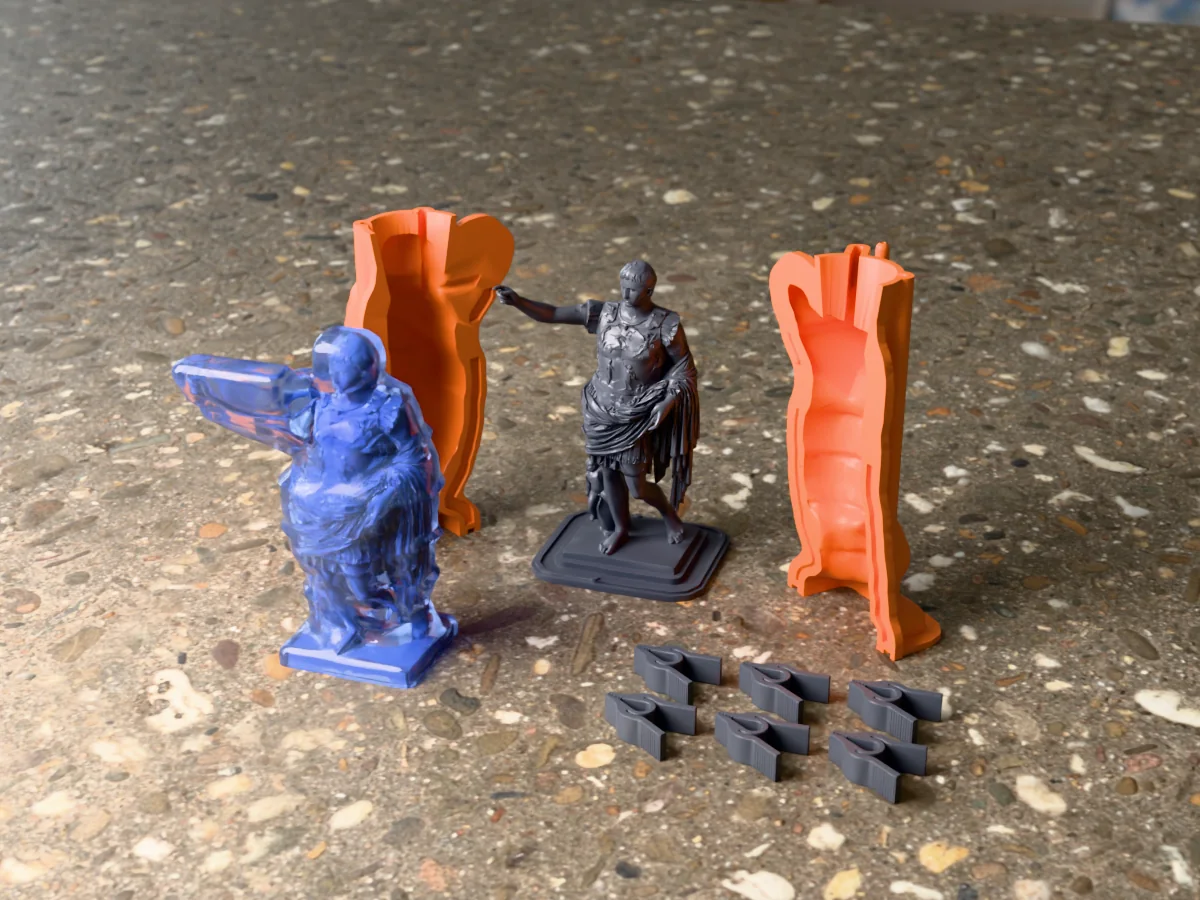 3D render of the Augustus of Prima Porta master on its printed charcoal base between the two orange hugging-shell halves, with the six printed clamps and the cured translucent blue silicone mold in front