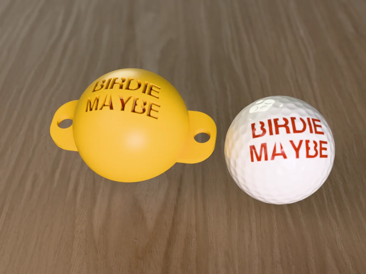 3D render of a yellow 3D-printed golf ball stencil with BIRDIE MAYBE cut through it, sitting on a golf ball, next to a ball marked with BIRDIE MAYBE in orange