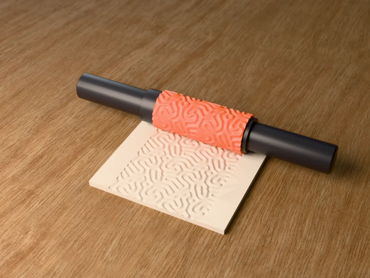 3D render of the printed brain coral textured rolling pin, its patterned sleeve between two dark handles, resting on a slab of clay it has pressed with brain coral