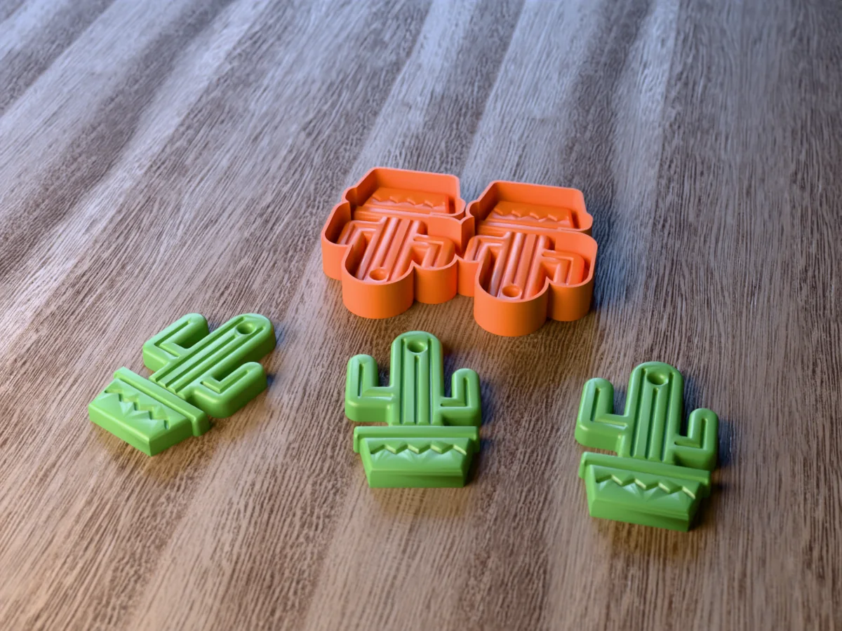 3D render of the printed caster for a two-cavity cactus freshie mold, with three green saguaro cactus car freshies in pots in front