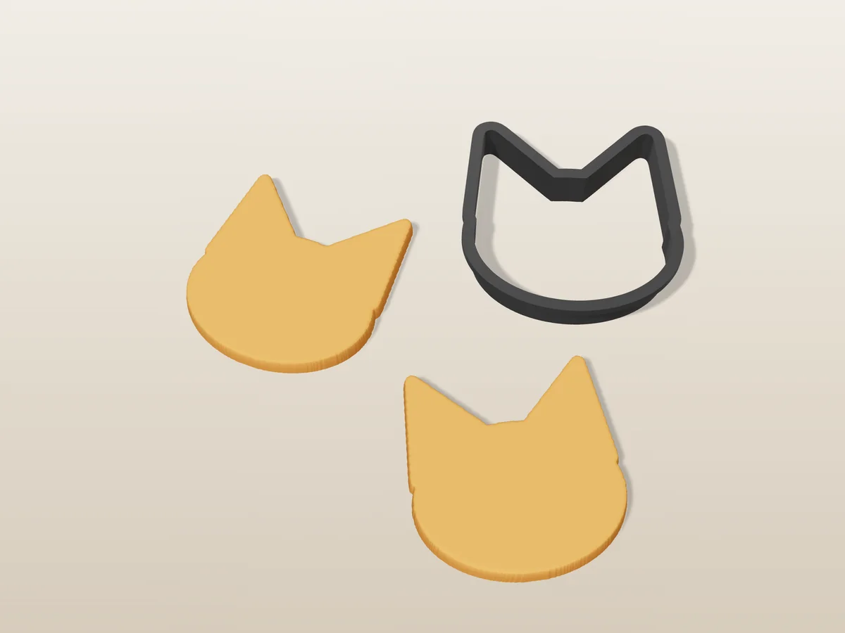 3D render of a black 3D-printed cat cookie cutter next to two golden baked cookies in the same shape