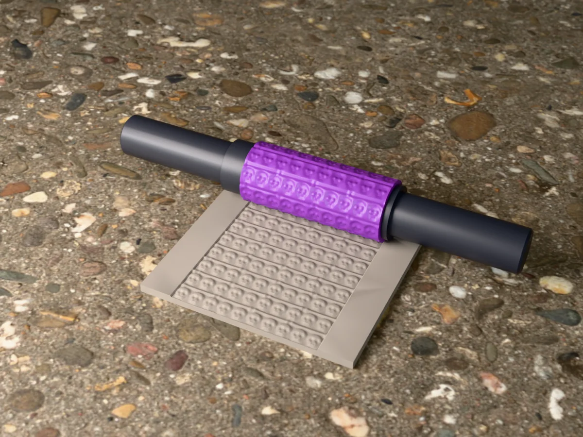 3D render of the printed catacomb skull wall textured rolling pin, its patterned sleeve between two dark handles, resting on a slab of clay it has pressed with a wall of skulls and bones