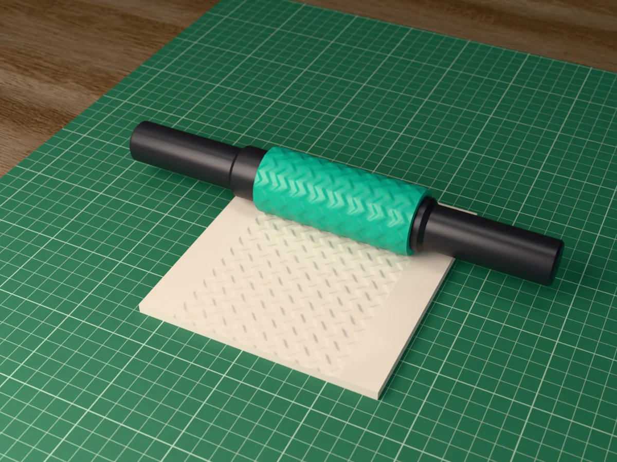 3D render of the printed chevron textured rolling pin, its patterned sleeve between two dark handles, resting on a slab of clay it has pressed with a chevron zigzag