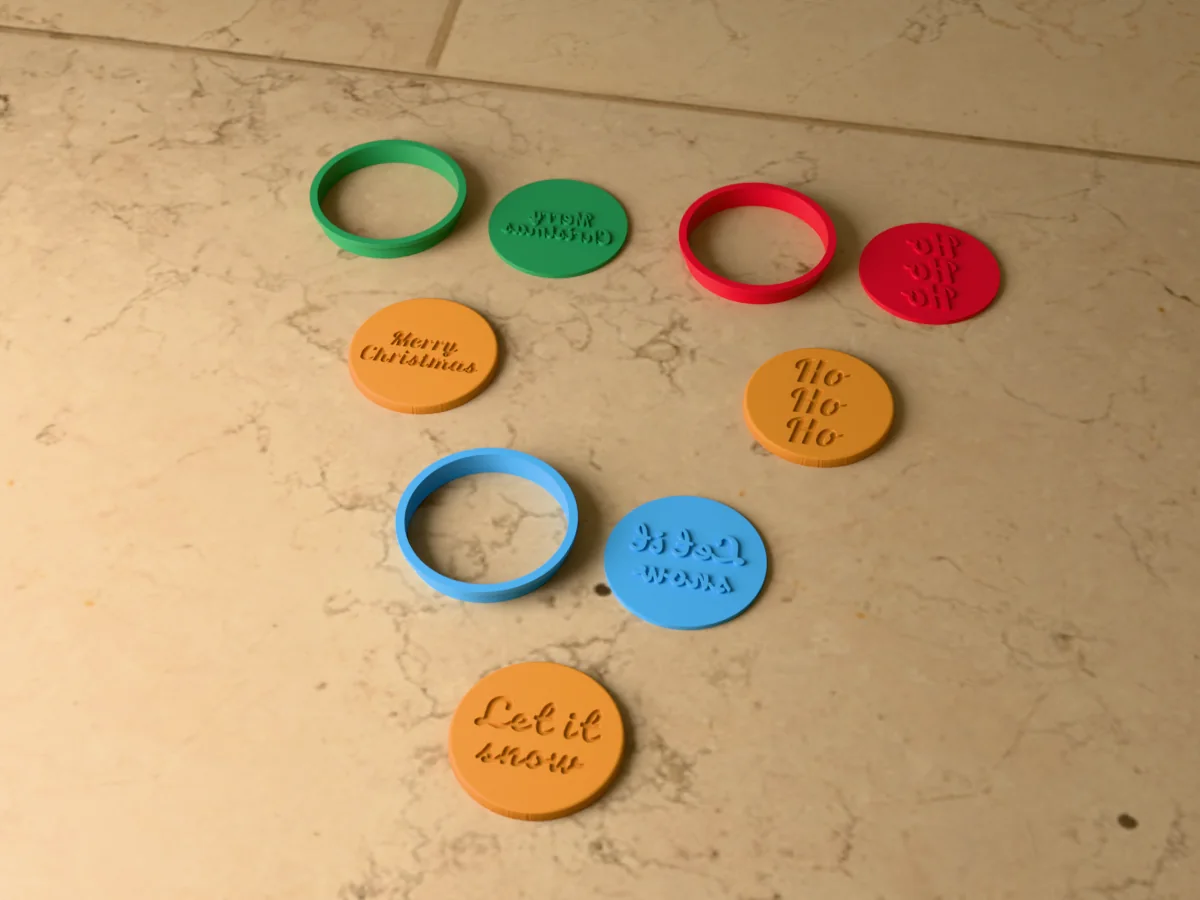 3D render of three 3D-printed round cookie cutters with their word stamps and a golden stamped cookie in front of each: Merry Christmas, Ho Ho Ho and Let it snow