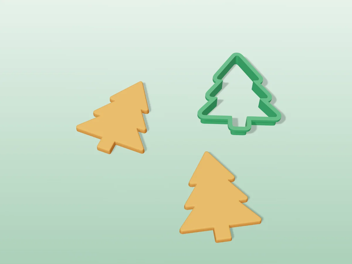 3D render of a green 3D-printed christmas tree cookie cutter next to two golden baked cookies in the same shape