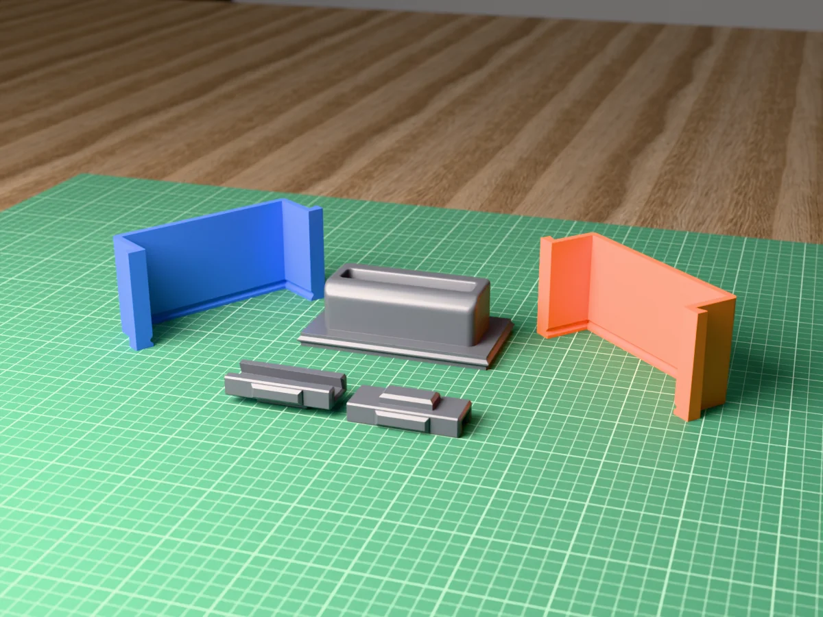 3D render of the concrete business card holder master with its slot, fused on its printed charcoal base between the orange and blue walls, with the charcoal clamps behind