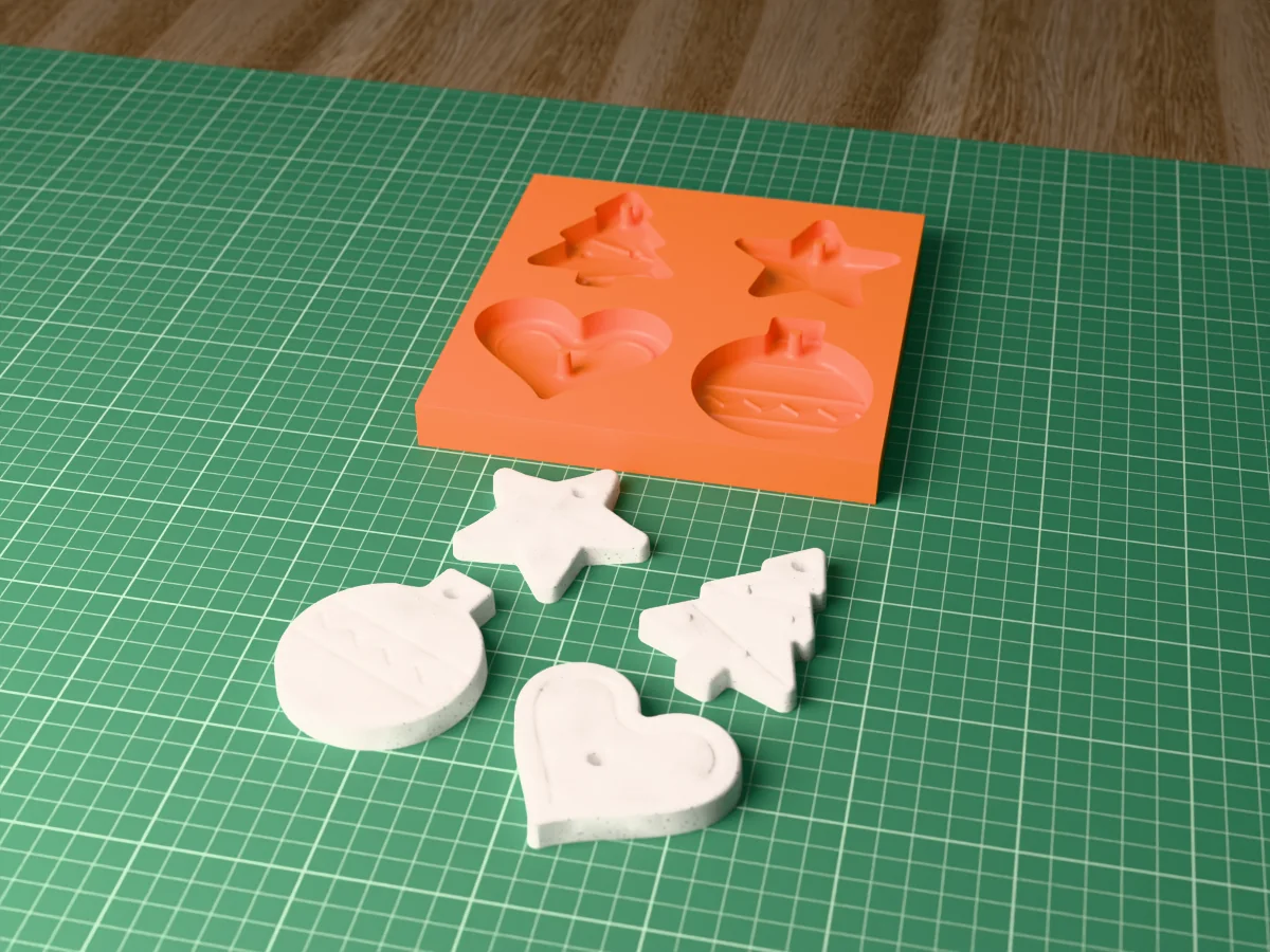 3D render of a printed orange tray with four ornament cavities, star, tree, bauble and heart, with the grey concrete ornaments in front