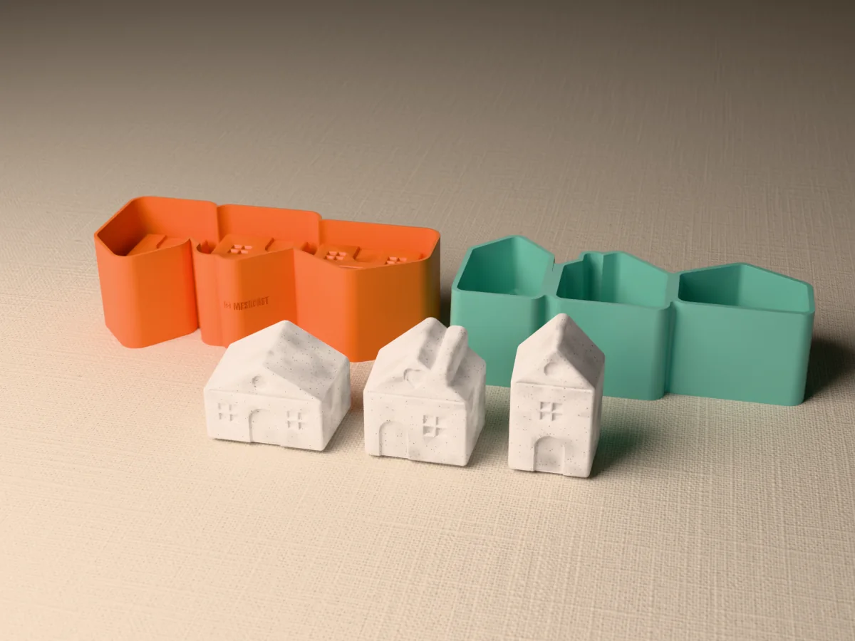 3D render of an orange printed caster beside a green silicone mold with three house-shaped cavities, with three small grey concrete houses with doors and windows standing in front