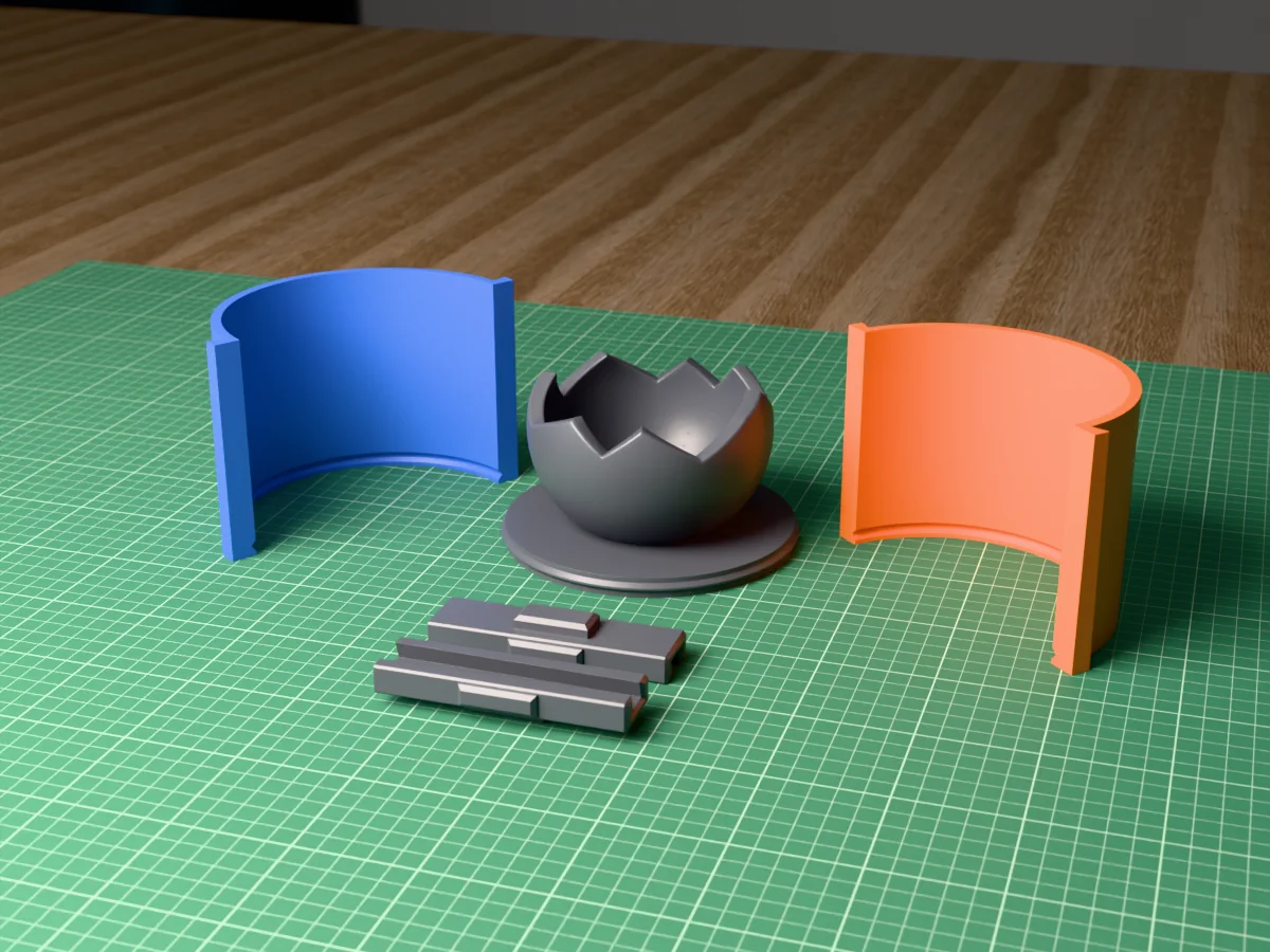 3D render of the cracked concrete sphere candle vessel master with its jagged rim, fused on its printed charcoal base between the orange and blue round walls, with the charcoal clamps in front