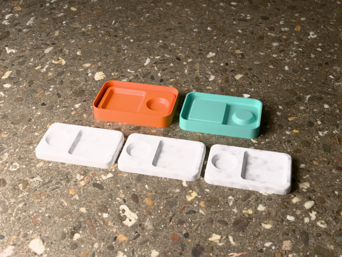 3D render of the printed caster for a silicone key tray mold beside the teal silicone tray it pours, with grey concrete key trays with two wells in front