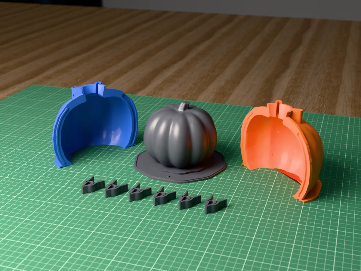 3D render of the ribbed concrete pumpkin master with its curved stem, fused on its printed charcoal base between the orange and blue shell halves, with the charcoal clamps in front