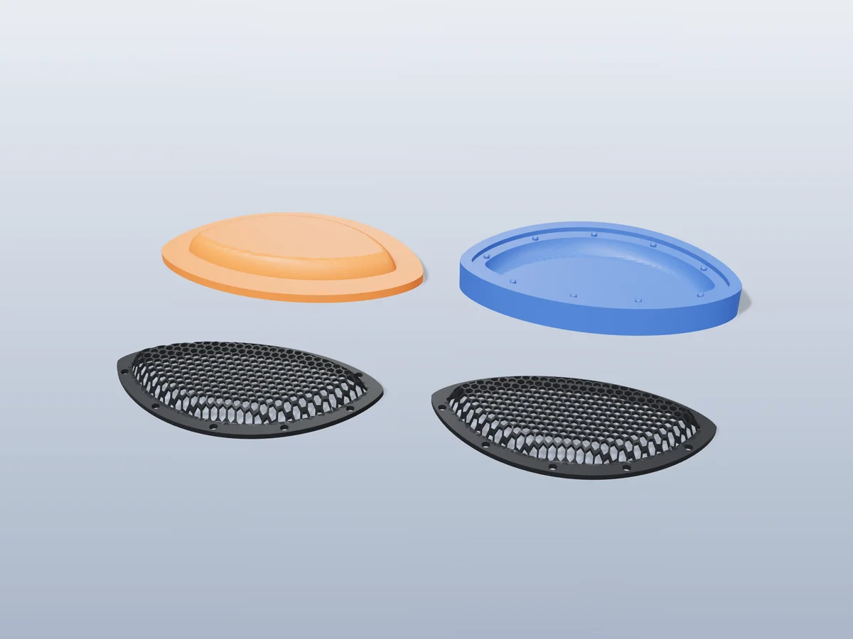 3D render of two curved black honeycomb cosplay eye meshes in front of the orange and blue press halves that form them