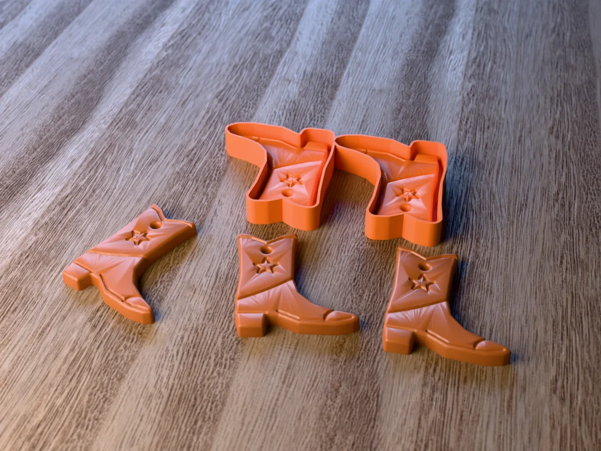 3D render of the printed caster for a two-cavity cowboy boot freshie mold, with three brown cowboy boot car freshies with a star and stitch lines in front