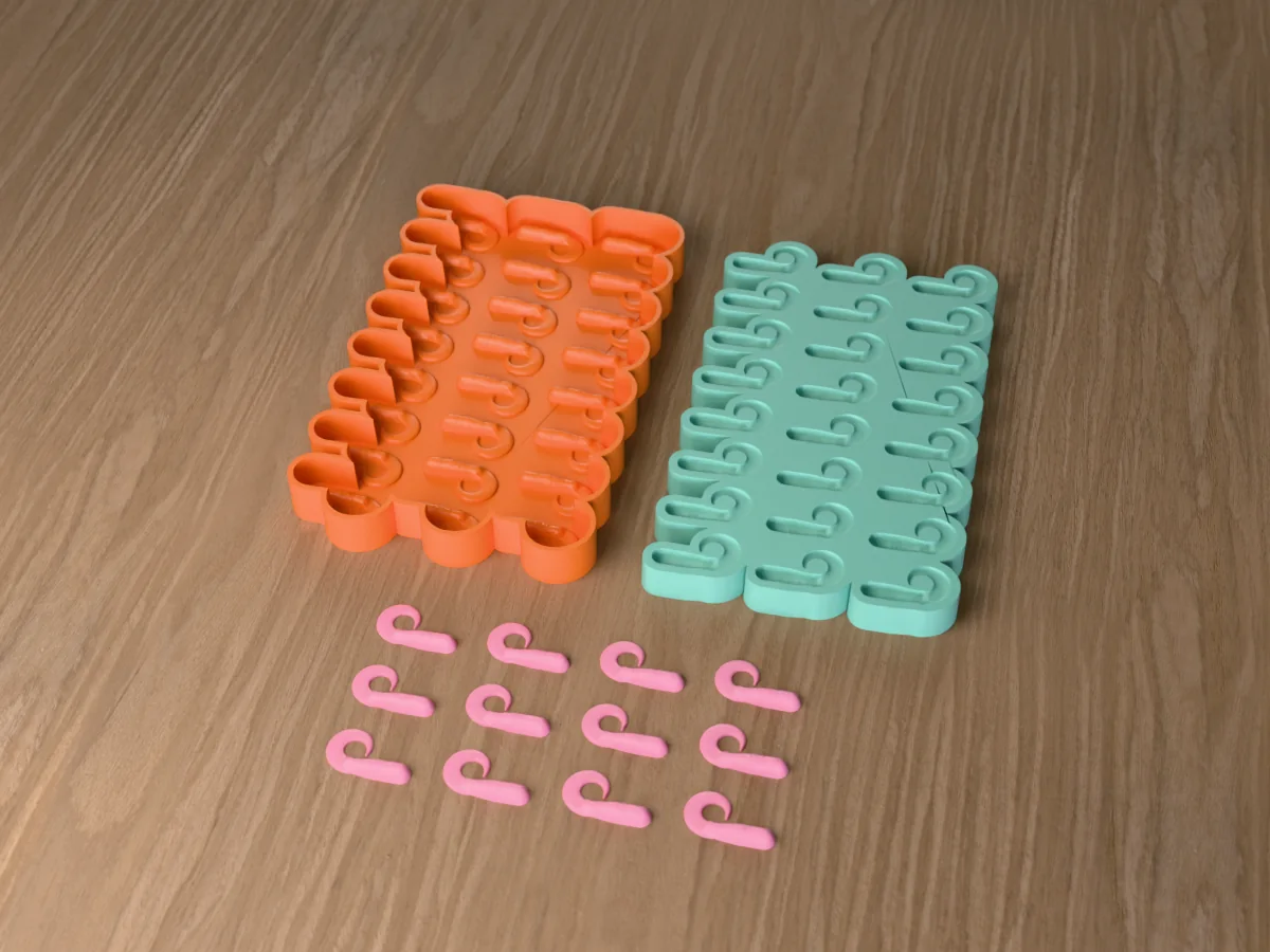 3D render of the printed caster for a twenty-four-cavity silicone crappie grub lure mold beside the silicone mold it pours, with pink soft plastic crappie grubs in front