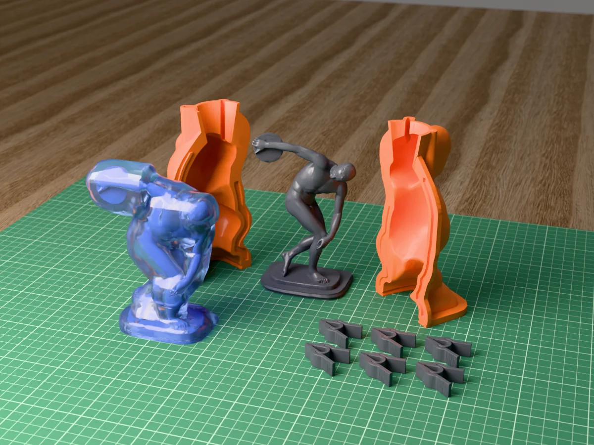 3D render of the Discobolus master on its printed charcoal base between the two orange hugging-shell halves, with the six printed clamps and the cured translucent blue silicone mold in front