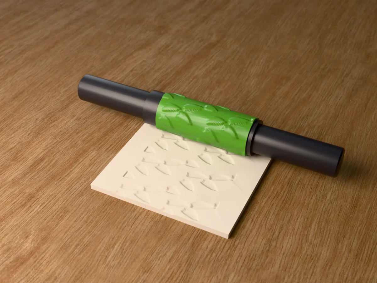 3D render of the printed fern leaf textured rolling pin, its patterned sleeve between two dark handles, resting on a slab of clay it has pressed with fern fronds
