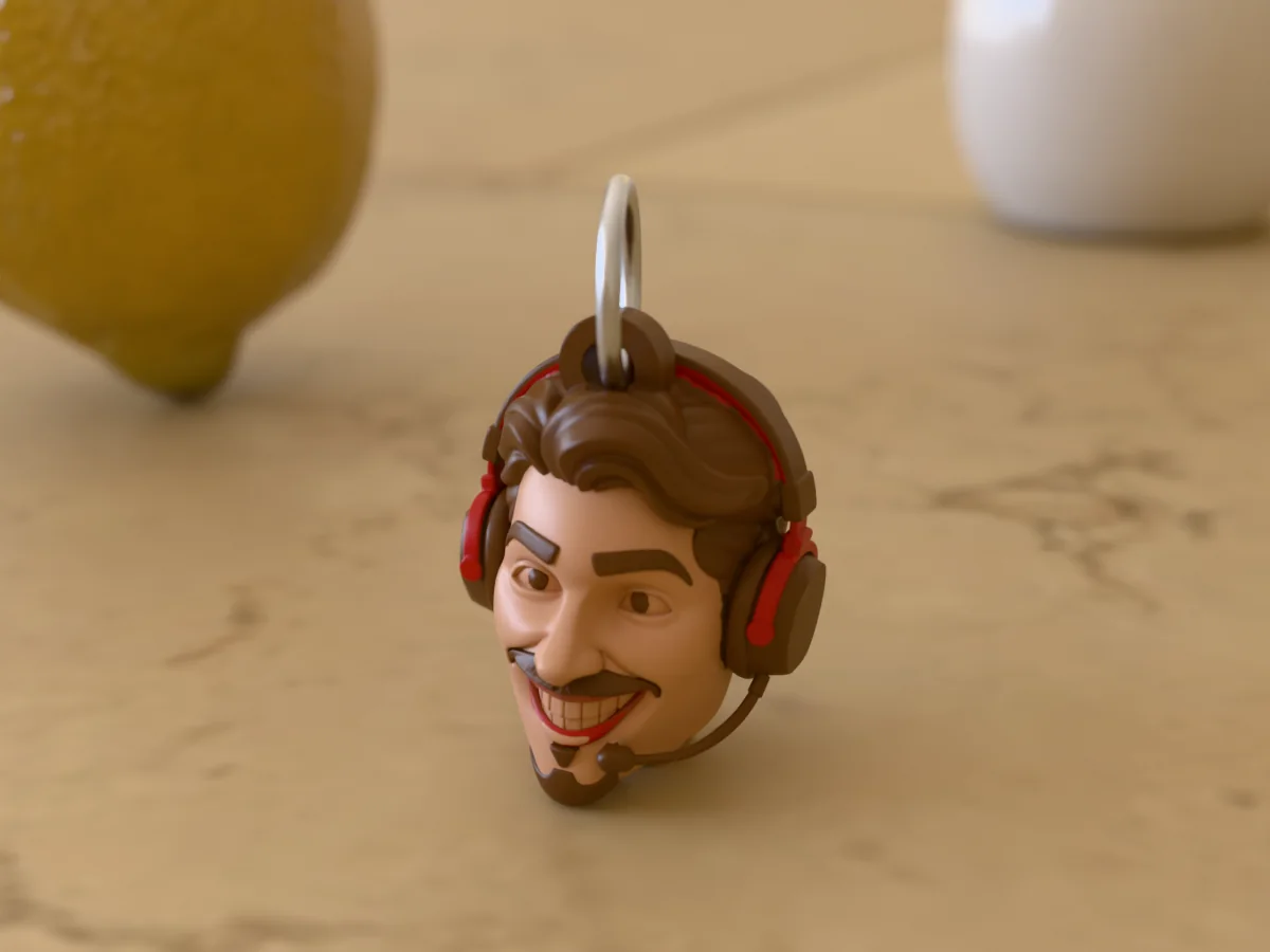 3D render of a 3D-printed head keychain of a grinning gamer in a red and black headset with a mic, painted in 6 colours, on a table
