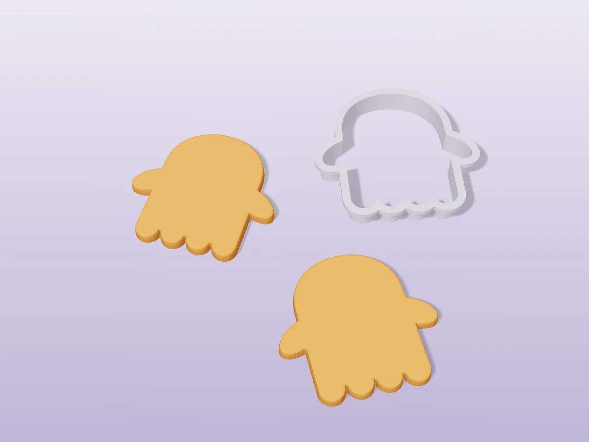 3D render of a pale grey 3D-printed ghost cookie cutter next to two golden baked cookies in the same shape