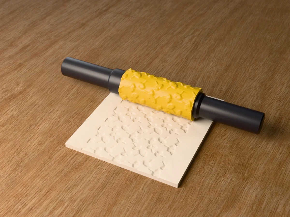 3D render of the printed ginkgo leaf textured rolling pin, its patterned sleeve between two dark handles, resting on a slab of clay it has pressed with ginkgo leaves