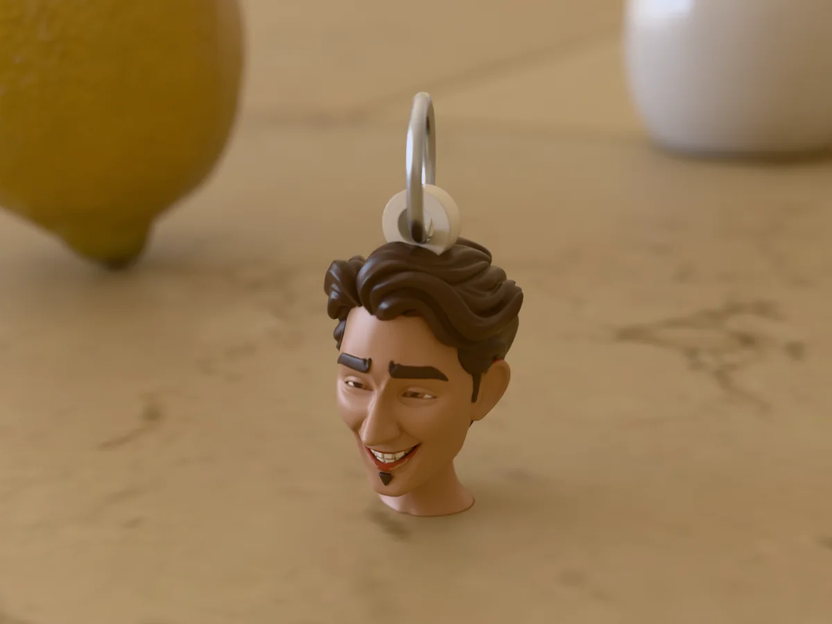 3D render of a 3D-printed head keychain of a guy with swept-back brown hair and a goatee, painted in 6 colours, on a table