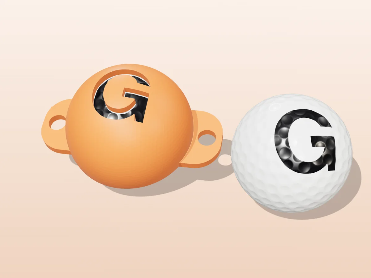 3D render of an orange 3D-printed golf ball stencil with the letter G cut through it, sitting on a golf ball, next to a ball marked with a black G