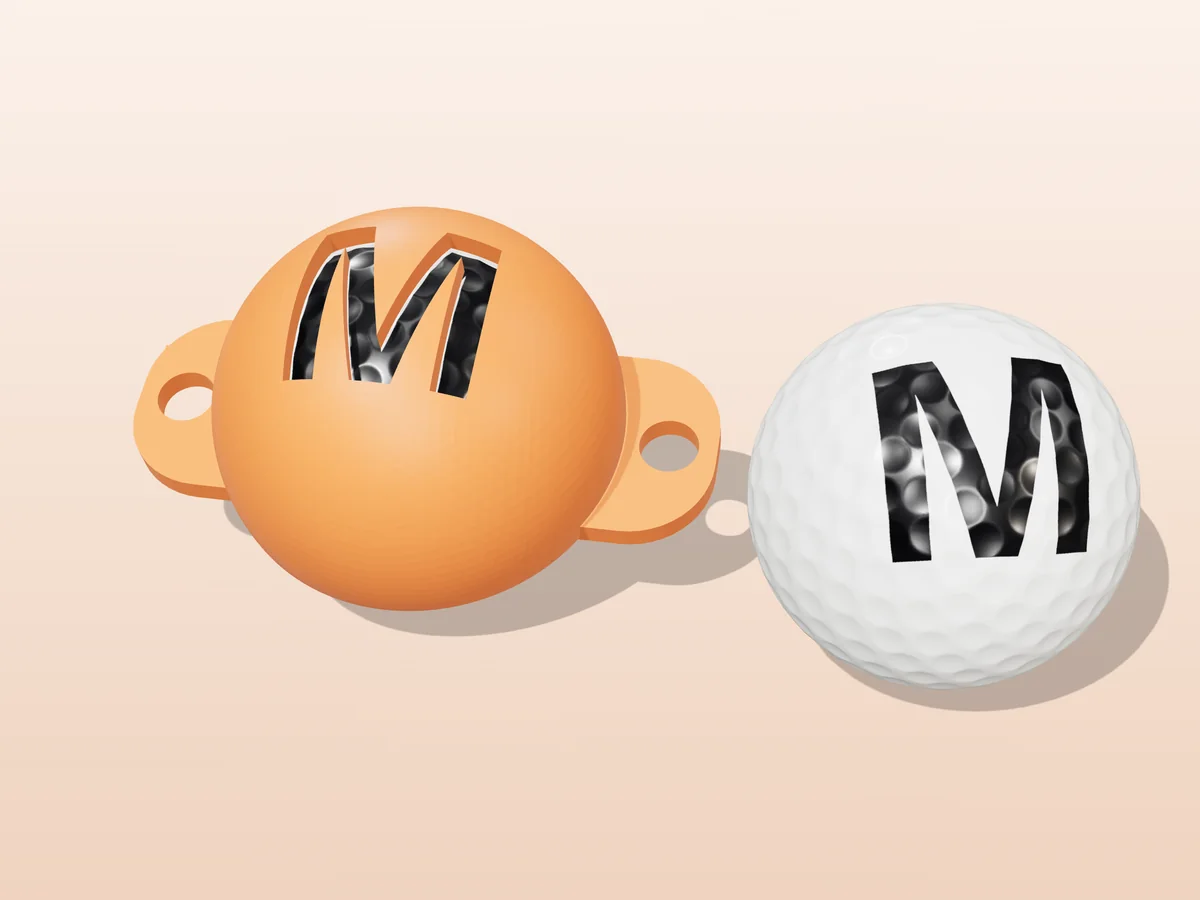 3D render of an orange 3D-printed golf ball stencil with the letter M cut through it, sitting on a golf ball, next to a ball marked with a black M