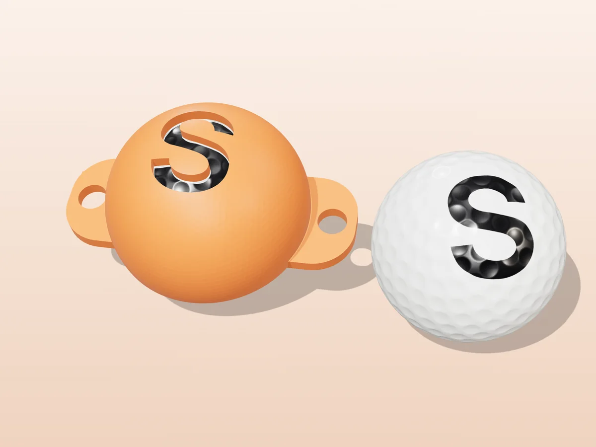 3D render of an orange 3D-printed golf ball stencil with the letter S cut through it, sitting on a golf ball, next to a ball marked with a black S