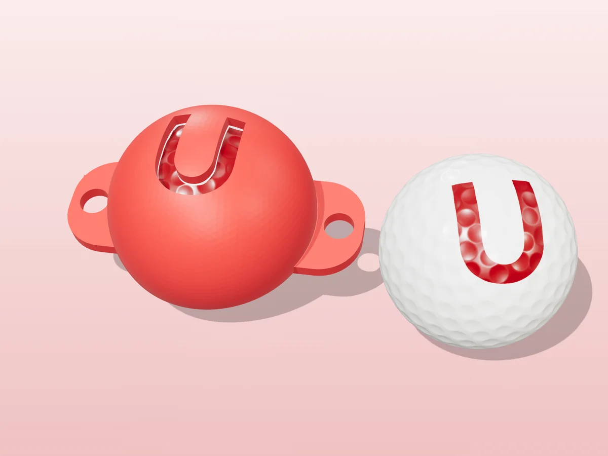 3D render of a red 3D-printed golf ball stencil with the letter U cut through it, sitting on a golf ball, next to a ball marked with a red U
