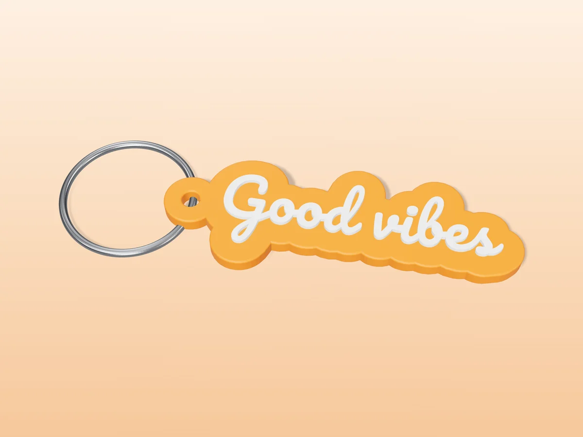 3D render of an orange and white 3D-printed Good vibes keychain with a steel split ring through its hole