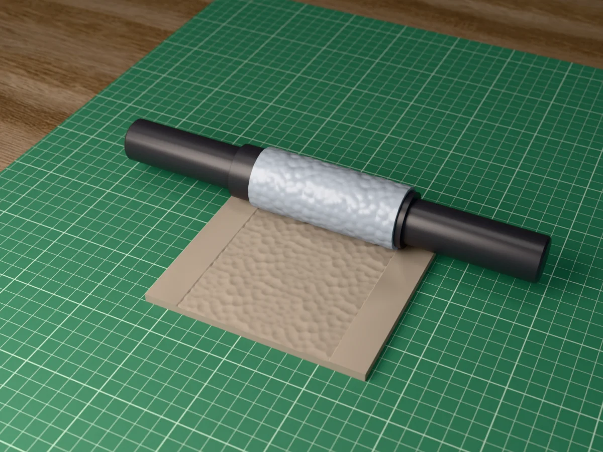 3D render of the printed hammered metal textured rolling pin, its patterned sleeve between two dark handles, resting on a slab of clay it has pressed with hammered dimples