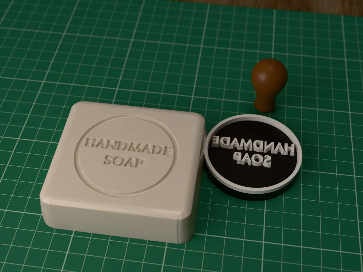 3D render of the printed handmade soap stamp, face up next to its brown handle, and a bar of soap with the stamp pressed into it