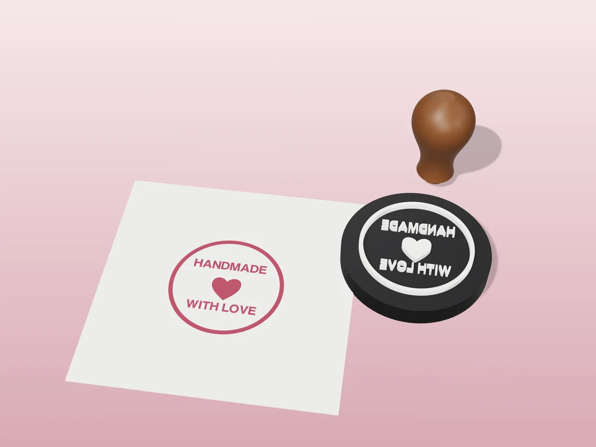 3D render of the printed handmade with love stamp, face up next to its brown handle, and its berry ink print on a sheet of paper