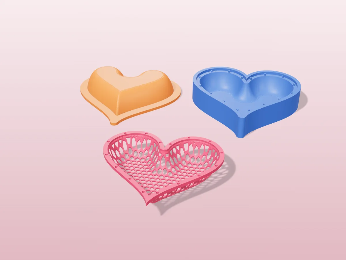 3D render of a pink heart shaped honeycomb mesh dish in front of the orange and blue press halves that form it