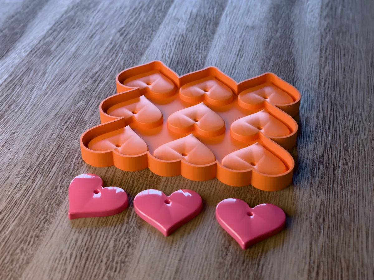3D render of the printed caster for a nine-cavity heart resin keychain mold, with three glossy pink resin heart keychain blanks in front