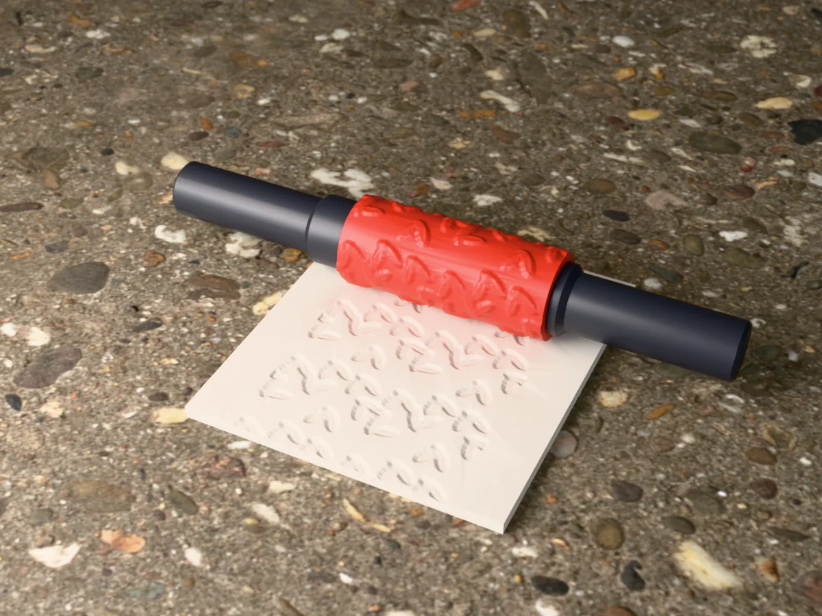 3D render of the printed holly and berry textured rolling pin, its patterned sleeve between two dark handles, resting on a slab of clay it has pressed with holly and berries