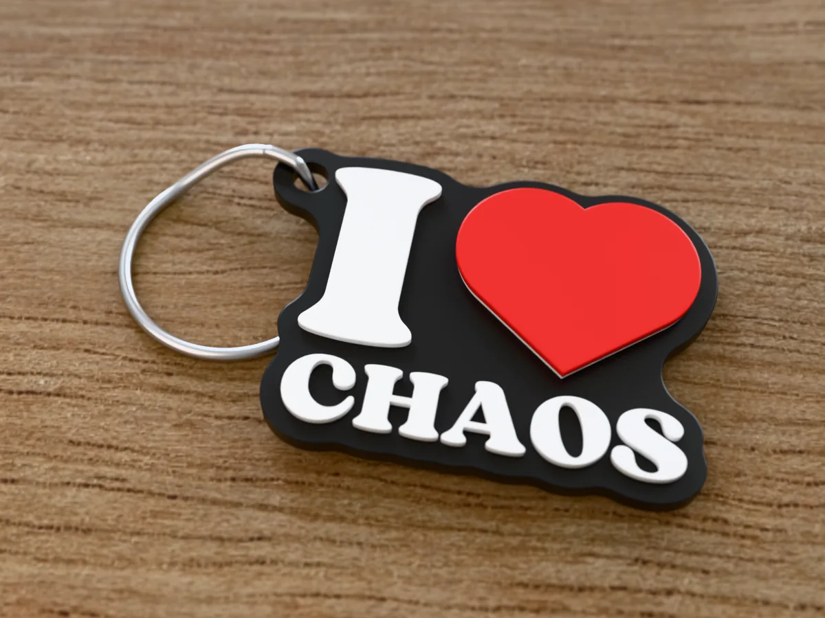 3D render of a black, white and red 3D-printed I love chaos keychain with a steel split ring through its hole