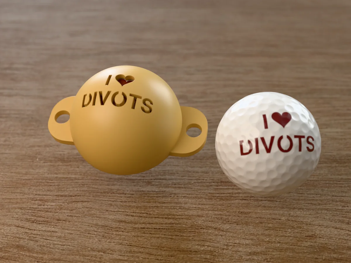 3D render of a sand 3D-printed golf ball stencil with I (heart) DIVOTS cut through it, sitting on a golf ball, next to a ball marked with I (heart) DIVOTS in brick red