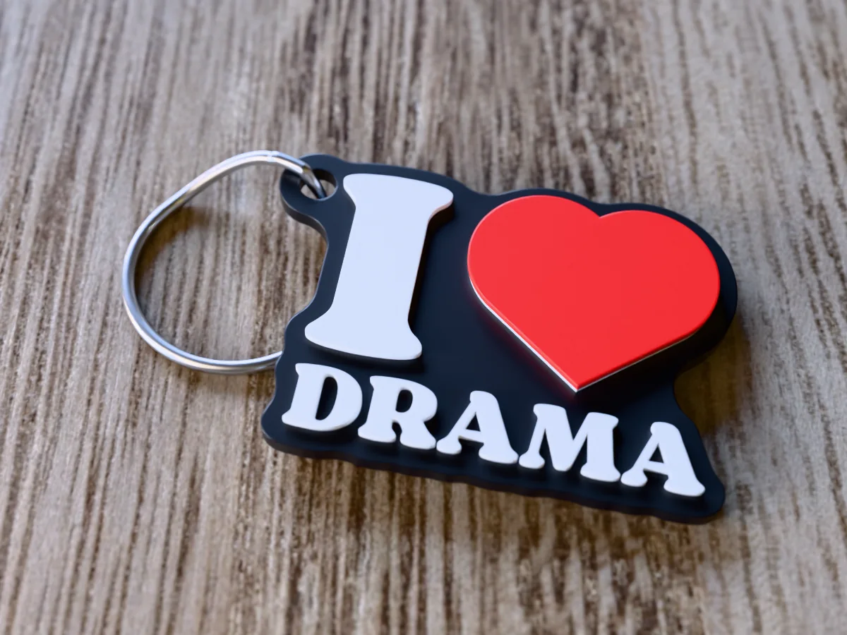 3D render of a black, white and red 3D-printed I love drama keychain with a steel split ring through its hole