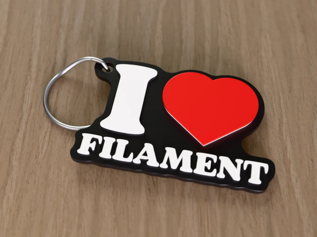 3D render of a black, white and red 3D-printed I love filament keychain with a steel split ring through its hole