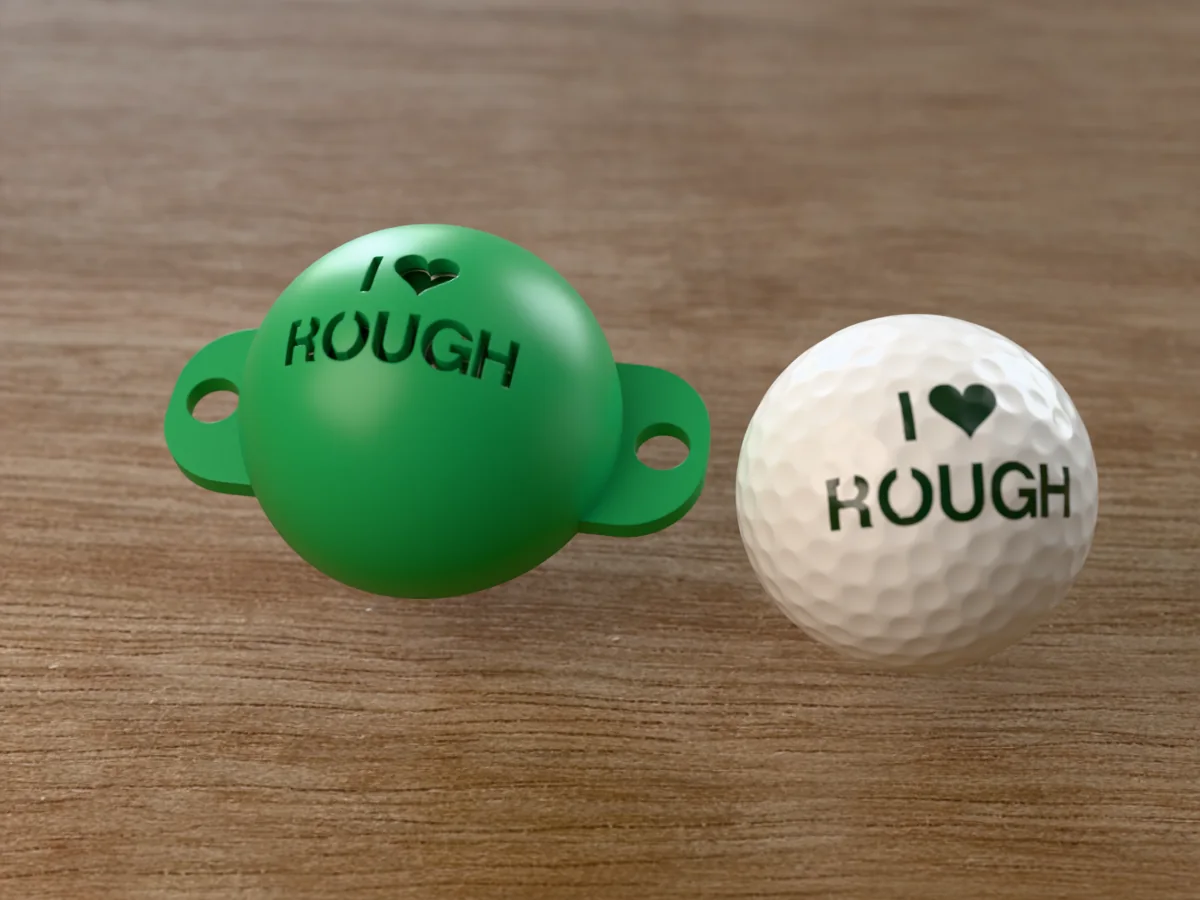 3D render of a green 3D-printed golf ball stencil with I (heart) ROUGH cut through it, sitting on a golf ball, next to a ball marked with I (heart) ROUGH in green