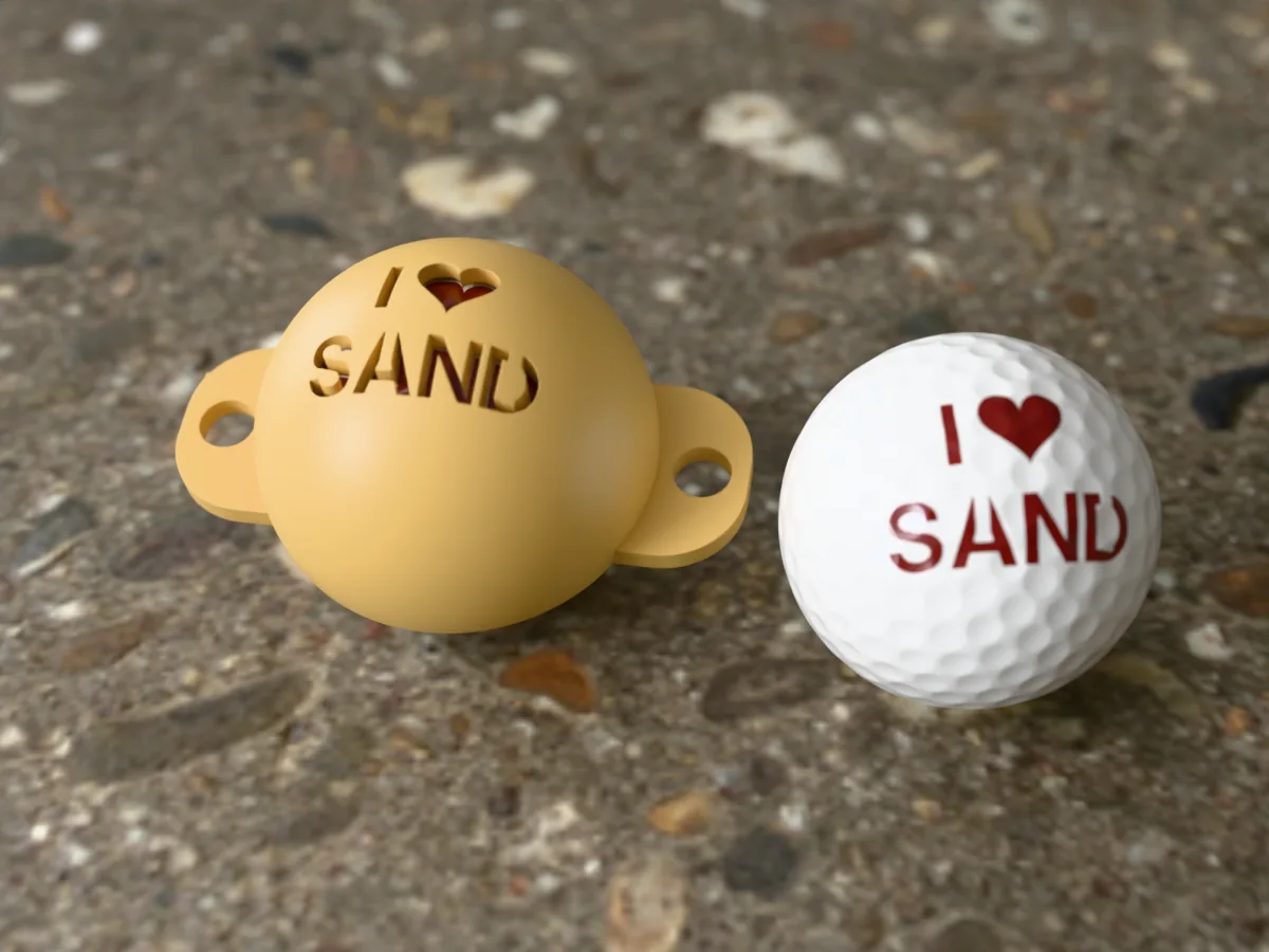 3D render of a sand 3D-printed golf ball stencil with I (heart) SAND cut through it, sitting on a golf ball, next to a ball marked with I (heart) SAND in brick red