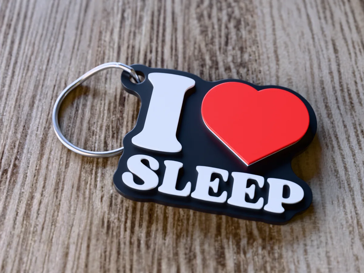 3D render of a black, white and red 3D-printed I love sleep keychain with a steel split ring through its hole