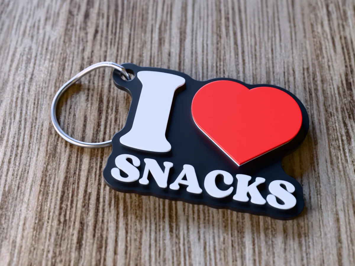 3D render of a black, white and red 3D-printed I love snacks keychain with a steel split ring through its hole