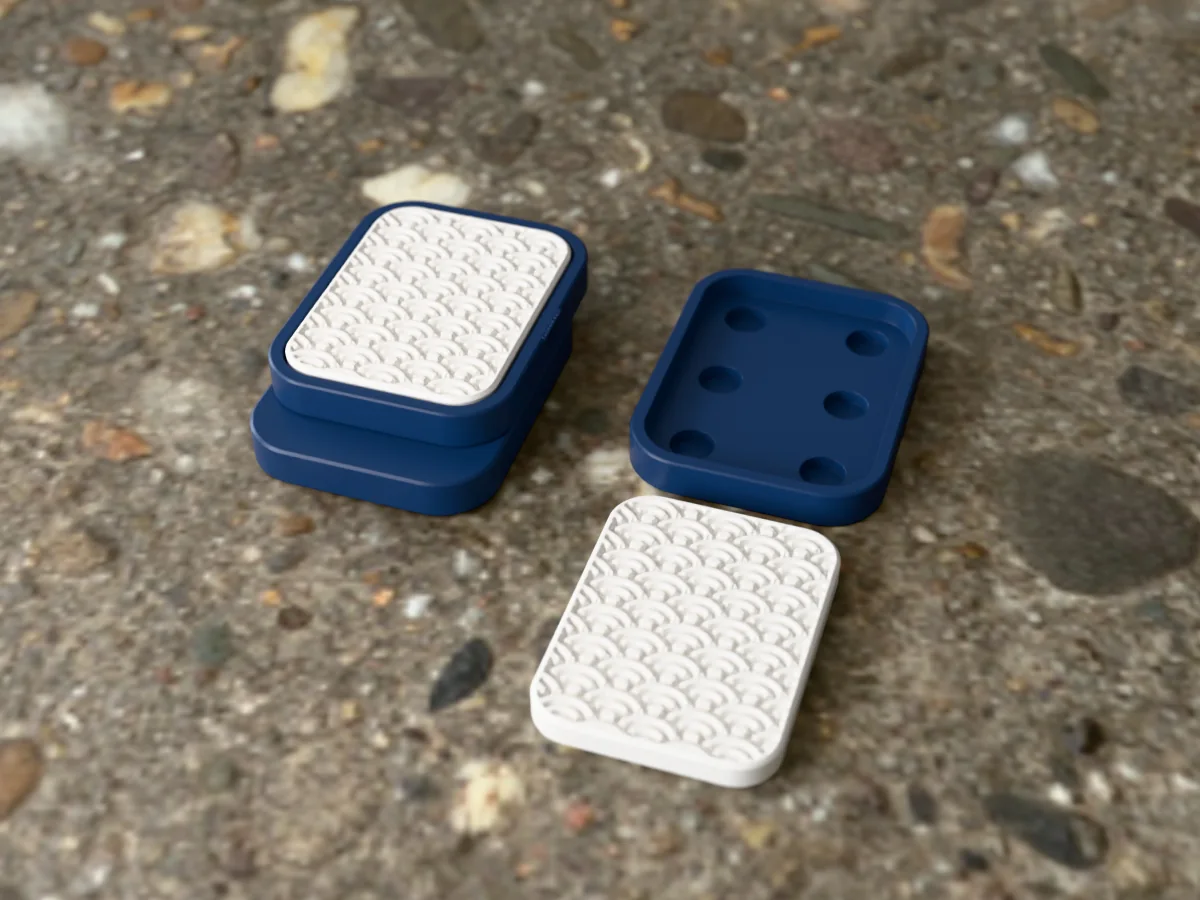 3D render of a navy and white 3D-printed magnetic fidget slider with a japanese waves texture, assembled, next to a spare plate and insert