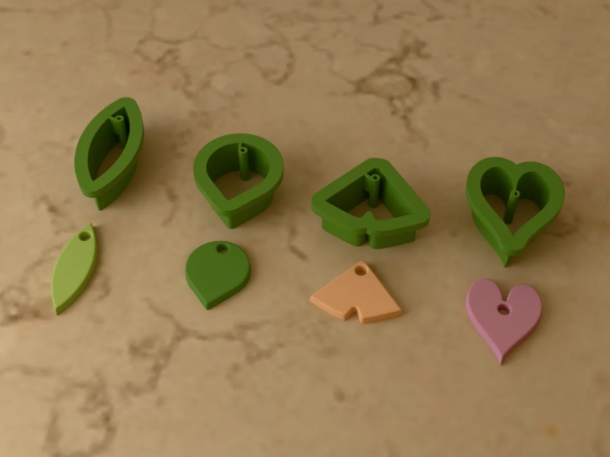 3D render of four 3D-printed green polymer clay earring cutters (olive leaf 36 mm, eucalyptus leaf 26 mm, ginkgo leaf 30 mm and heart leaf 30 mm) with the clay earring pieces they cut in front