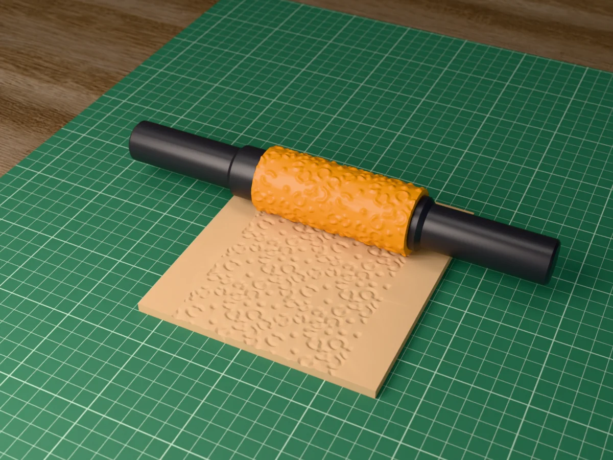 3D render of the printed leopard print textured rolling pin, its patterned sleeve between two dark handles, resting on a slab of clay it has pressed with a leopard print