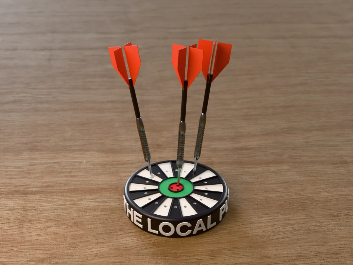 3D render of the printed personalized dart holder: a round black case with THE LOCAL PUB raised in white round its side, a black and white dartboard face with a green ring and red bullseye, and three darts standing in it