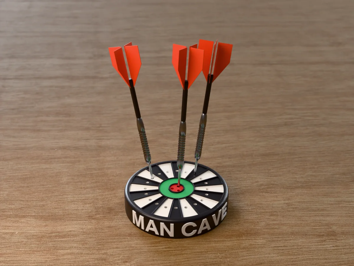 3D render of the printed personalized dart holder: a round black case with MAN CAVE raised in white round its side, a black and white dartboard face with a green ring and red bullseye, and three darts standing in it