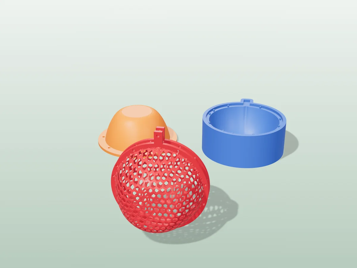3D render of a red honeycomb mesh Christmas ball ornament with a cap and hanging hole, in front of the orange and blue press halves that form it
